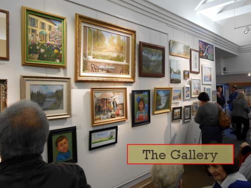 the gallery.  paintings on the wall and people viewing close and far